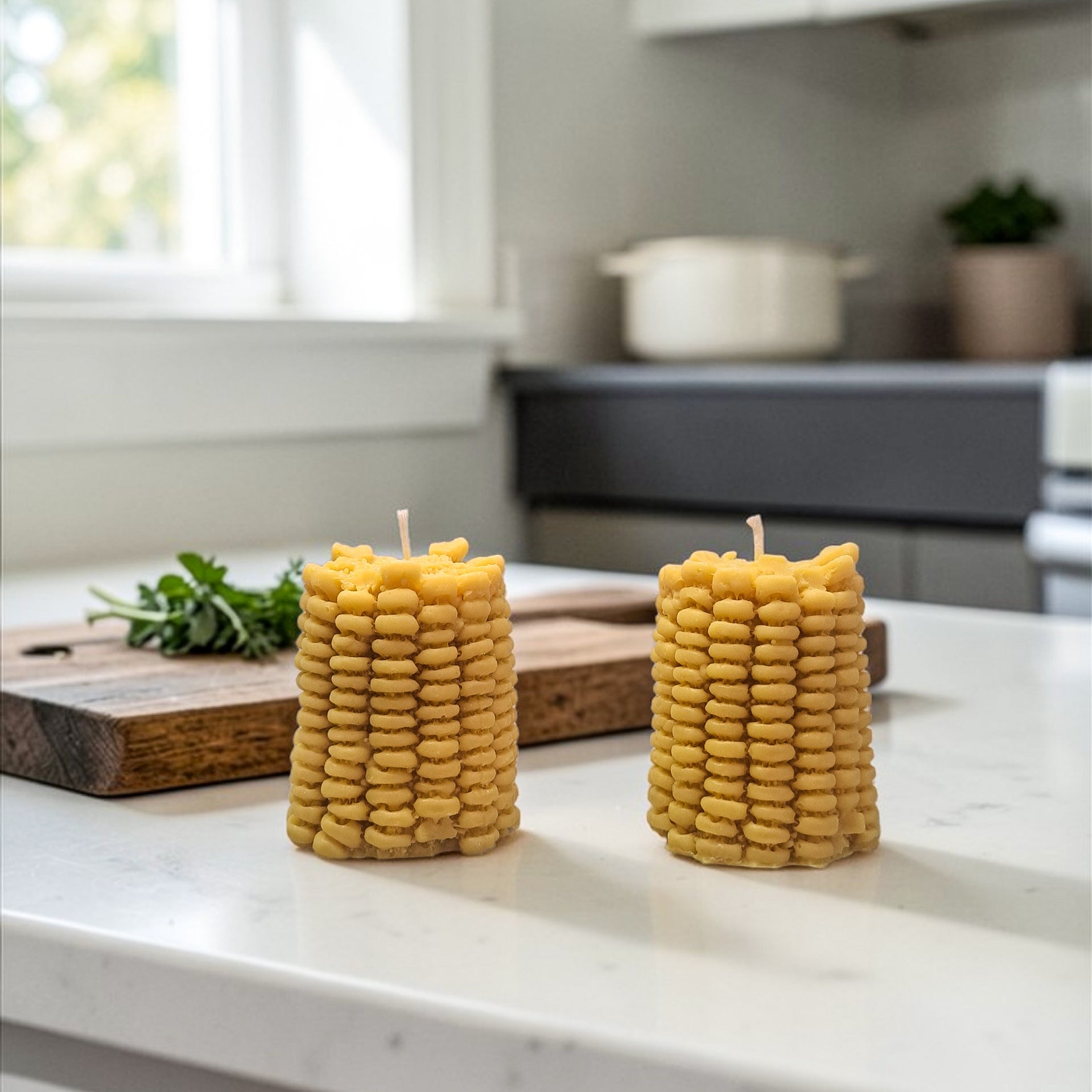 Corn soy wax candles on a kitchen counter with a window and pot in the background.