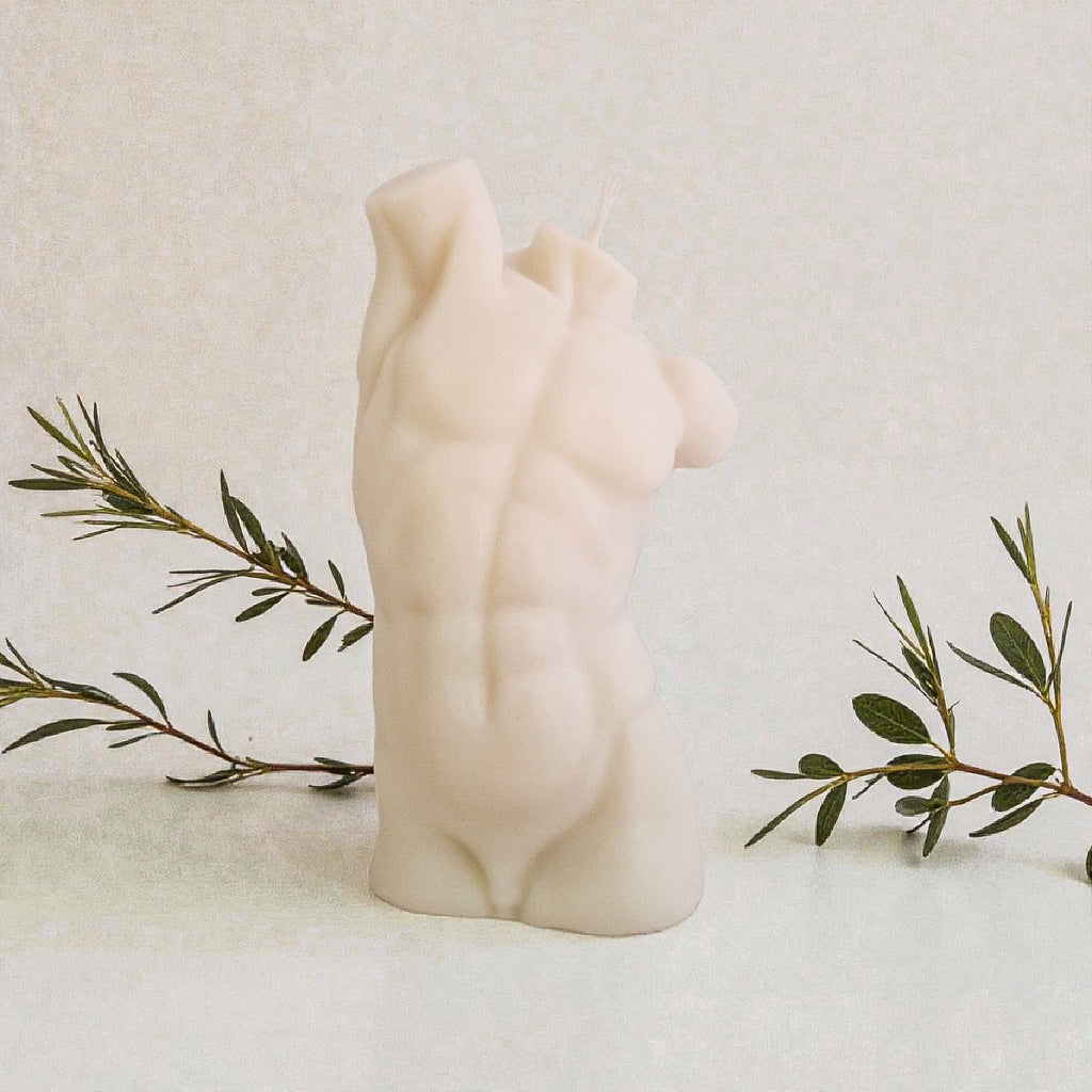 Candle shaped of a male torso on a marble surface with a branch of olives.