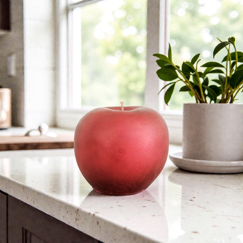 Red apple soy wax candle on a kitchen counter with a window in the background