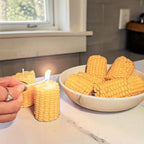 Corn on the cob soy wax candles being lit with a bowl of corn in the background.