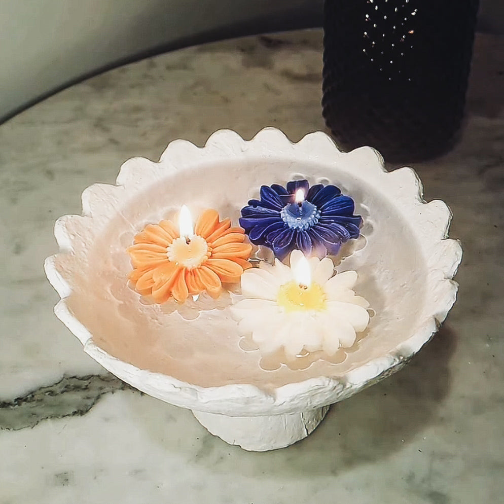 Decorative candle holder with three colourful daisy soy wax candles candles on a marble surface
