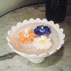Decorative candle holder with three colourful daisy soy wax candles candles on a marble surface