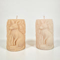 Two beige candles with kangaroo carvings on a white background