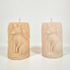 Two beige candles with kangaroo carvings on a white background
