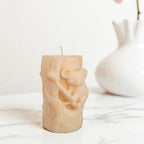 Soy wax candle shaped like a tree stump with a koala bear design on a white surface.