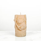 Soy wax candle shaped like a tree stump with a koala bear design on a white surface.