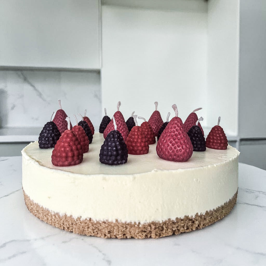 Decorative cake with hand poured strawberries, blackberries and raspberries soy wax birthday candles on a marble surface