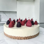 Decorative cake with hand poured strawberries, blackberries and raspberries soy wax birthday candles on a marble surface