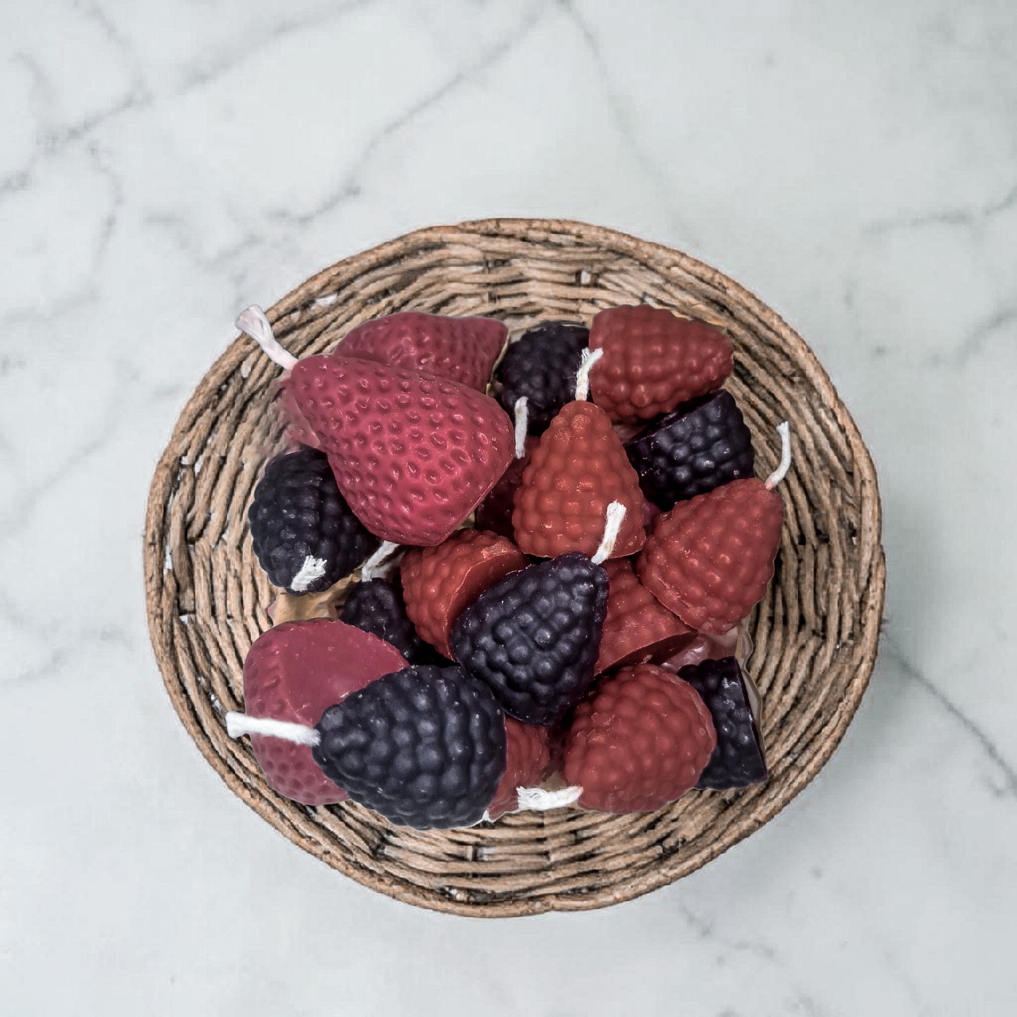 Wicker basket with strawberry, blackberry, and raspberry-shaped hand poured soy wax candles on a marble surface