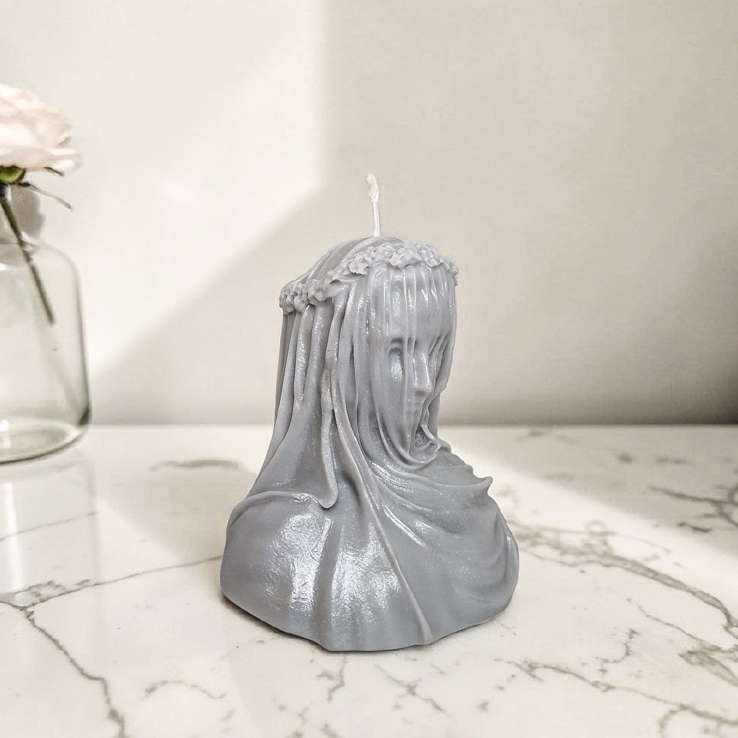Hand poured soy wax candle shaped like a bust with a veil on a marble surface