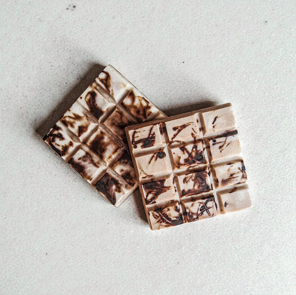 Marbled soy wax melt snap bars arranged on a neutral grey surface