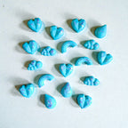Blue heart, cloud, and rainbow-shaped Blue soy wax melts in heart, cloud and rainbow shapes on a light grey background.
