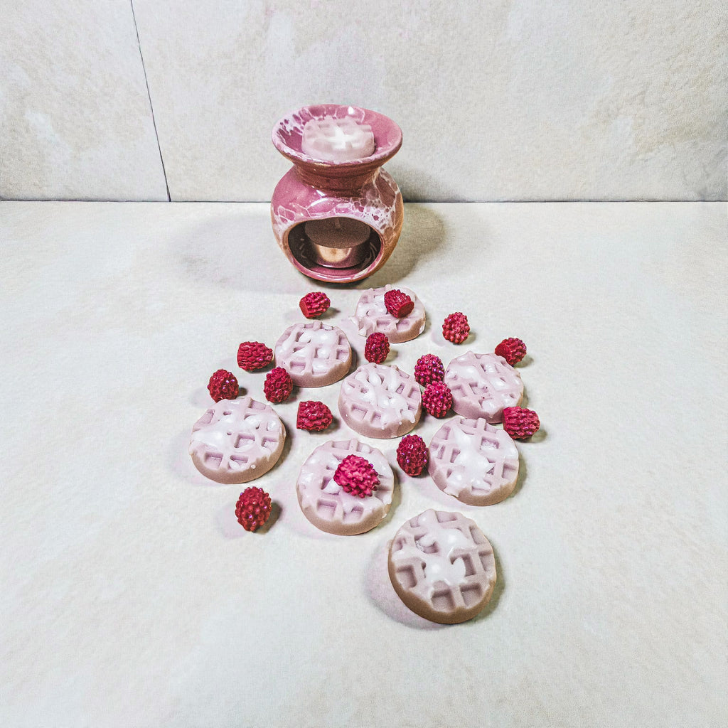 Waffle-shaped soy wax melts with pink icing and raspberry detailing arranged on a light surface