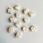White soy wax melts in star and heart shapes with gold dust on a light grey surface