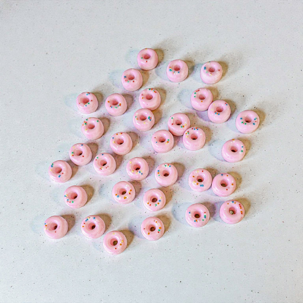 Pink donut-shaped soy wax melts with sprinkles on a light grey background
