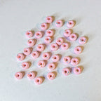 Pink donut-shaped soy wax melts with sprinkles on a light grey background