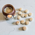 Wax melt burner with lit candle and beige floral soy wax melts displayed on a light background