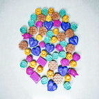 Assorted colorful soy wax melts in heart, flower and waffle shapes on a white background.