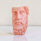 Candle shaped like a face with a beard on a white surface