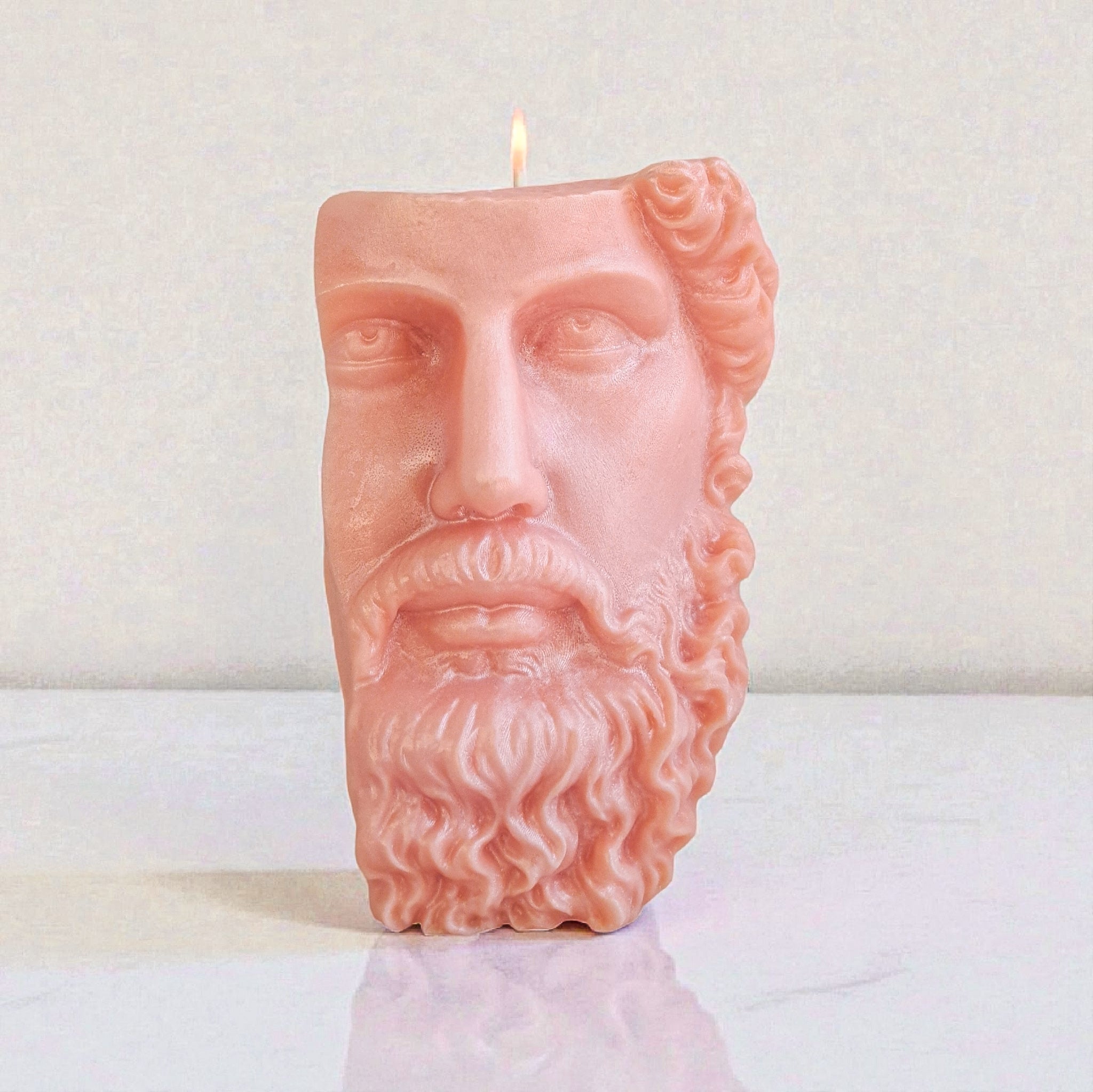 Candle shaped like a face with a beard on a white surface
